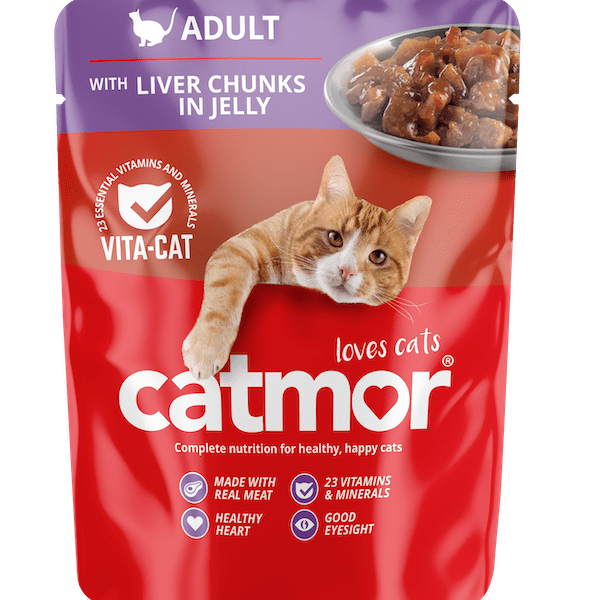 Product packaging for Catmor Adult Wet Cat Food, with a vibrant red and purple pouch design. The top purple section features a white cat silhouette and the word "ADULT" with the product description "WITH LIVER CHUNKS IN JELLY." A small bowl of the chunky, brown wet food is visible in the upper right corner. A ginger and white cat is shown playfully reaching its paw and head over the main red section, which displays the large white logo "catmor" and the slogan "loves cats." Key benefits are listed at the bottom with icons: "MADE WITH REAL MEAT," "23 VITAMINS & MINERALS," "HEALTHY HEART," and "GOOD EYESIGHT."