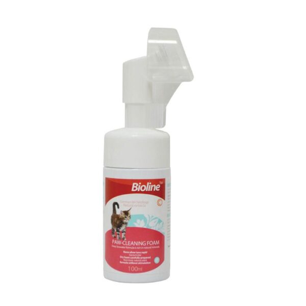 This image displays the Bioline Cat Paw-Cleaning Foam (100 ml) bottle, which is white with a red label and includes an innovative, integrated silicone soft brush head visible beneath a clear protective cap. The bottle's label highlights that the product uses "German technology" and "Natural extracts" for cleaning.