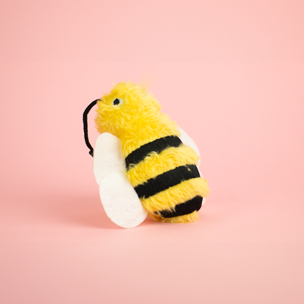 Zugo Bee Plush Catnip Toy, a plush toy shaped like a bee that is yellow and black with white wings and black antennae.
