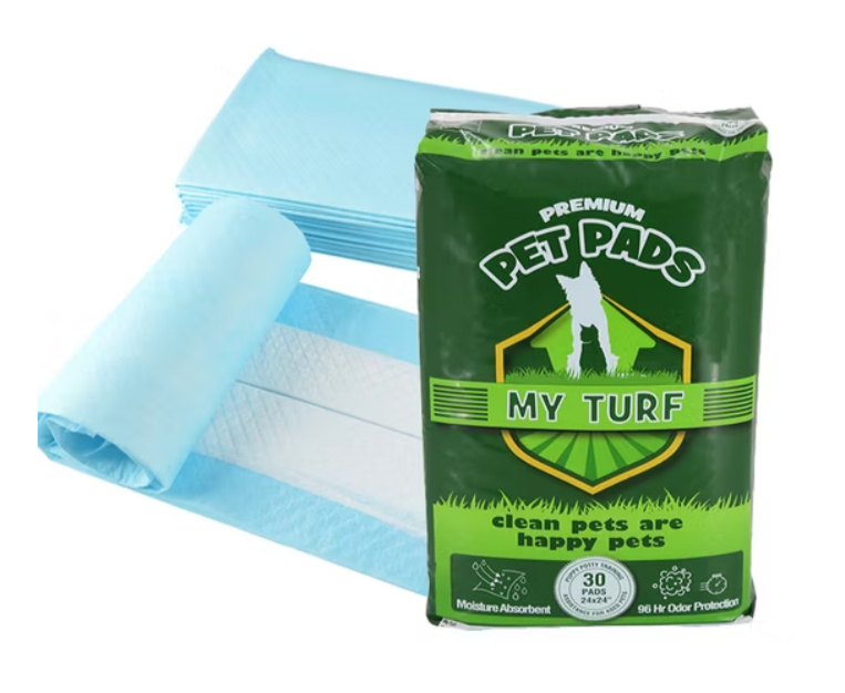My Turf Premium Pet Pads and Unrolled Pad, a stack of blue and white puppy training pads unrolled and lying behind a green retail bag of MY TURF PREMIUM PET PADS, highlighting the Moisture Absorbent and 96 Hr Odor Protection features.
