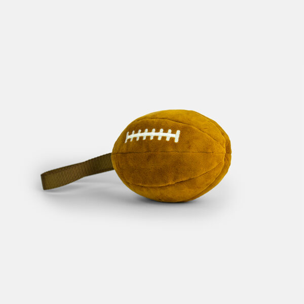 Plushball Plush Dog Toy, a brown plush toy shaped like a football with white stitching on top and a fabric loop handle on the side.